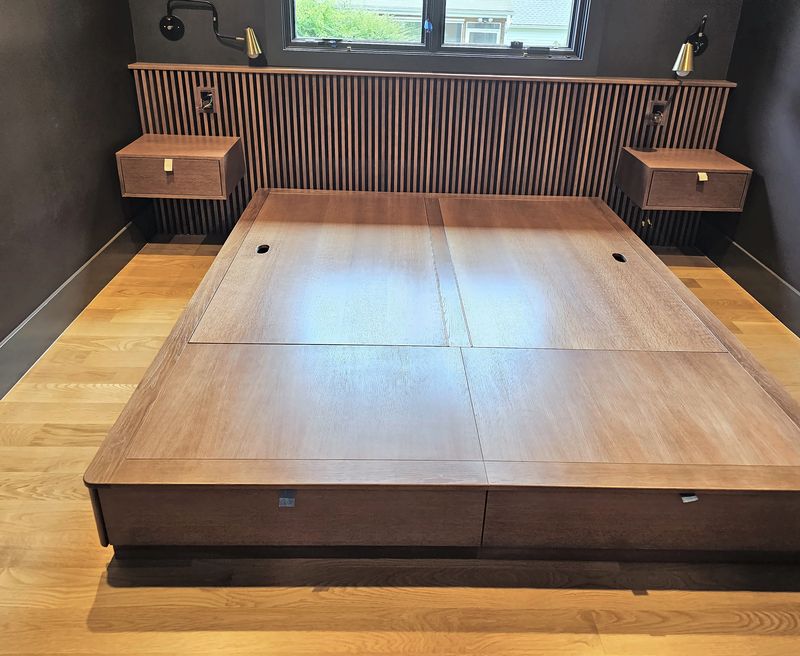 Walnut platform bed in front of a slatted walnut headboard wall with two floating walnut nightstands