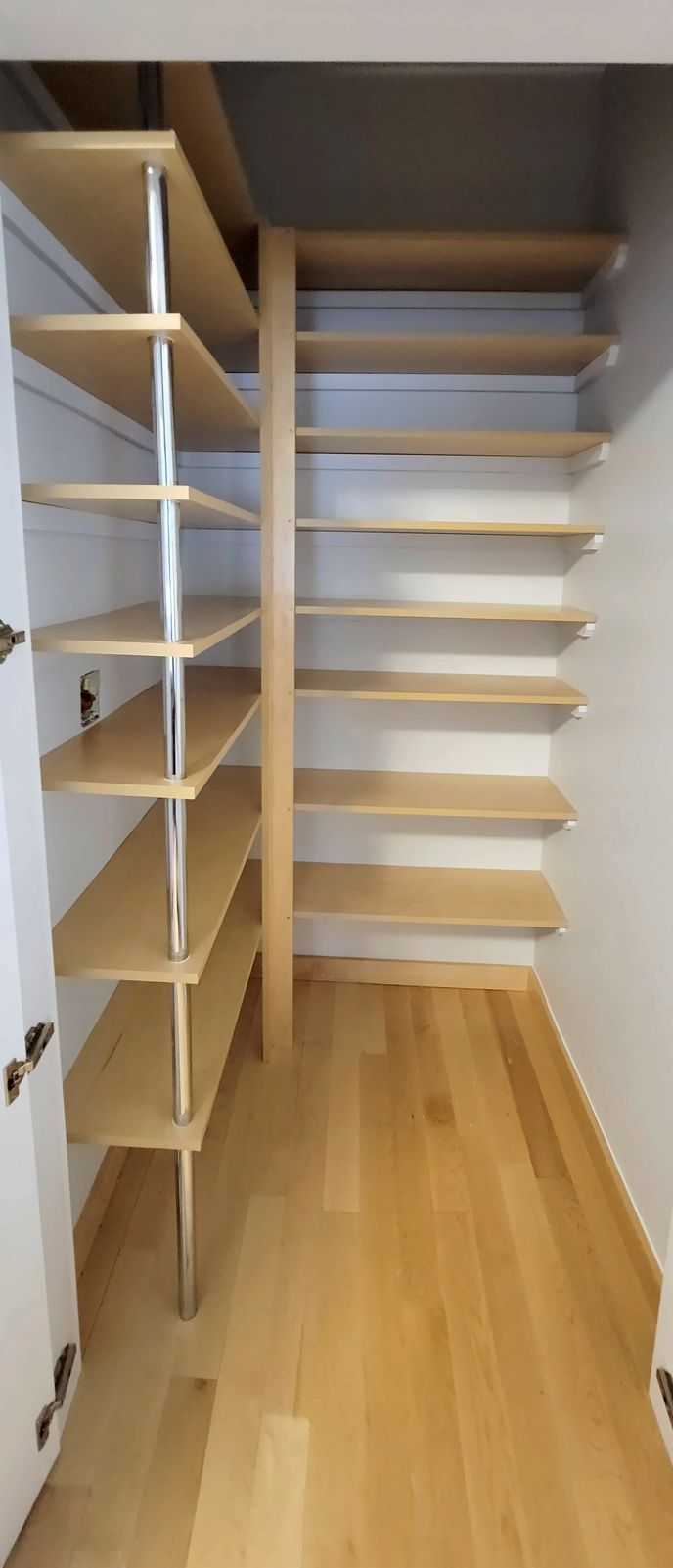 Walk-in pantry lined with light maple adjustable shelves