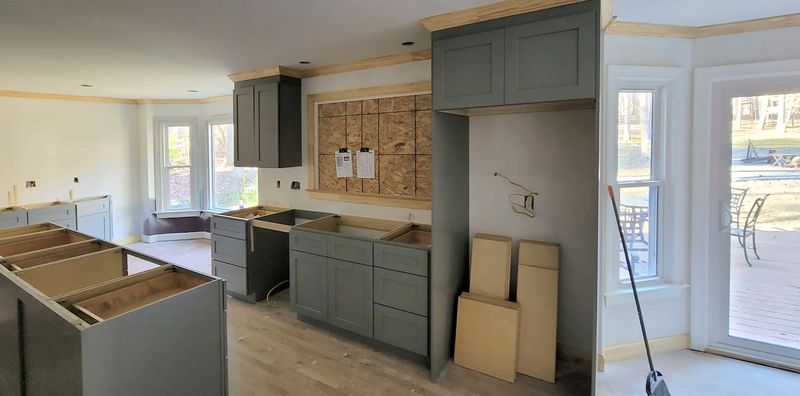 Kitchen during installation: gray cabinets and an island set in place without counters yet
