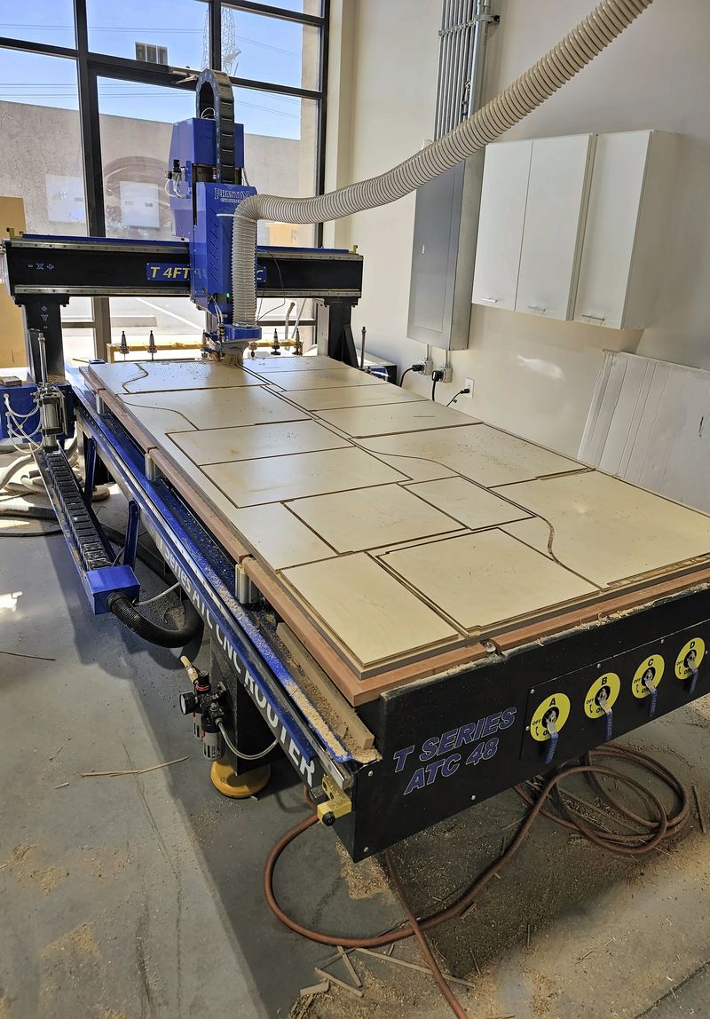 CNC router table in the shop with a sheet of cabinet parts freshly cut out