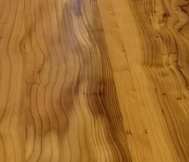 Close-up of a finished solid-wood top with golden, knotty grain