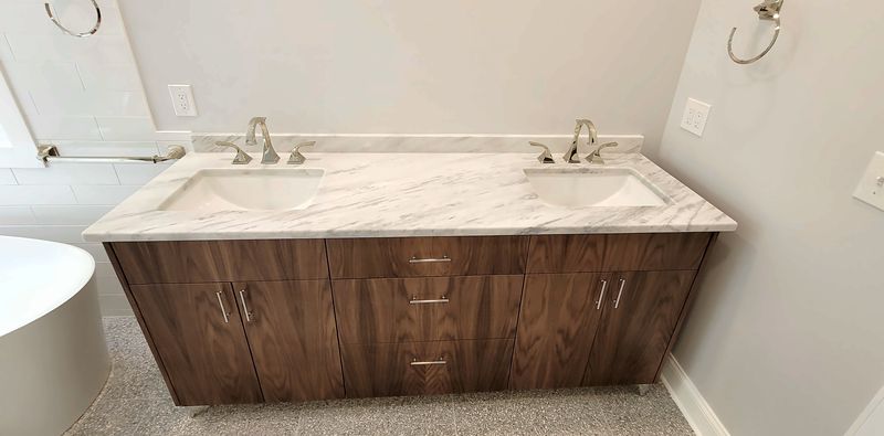 Walnut double vanity with flat-panel doors and drawers, a white marble top and two undermount sinks